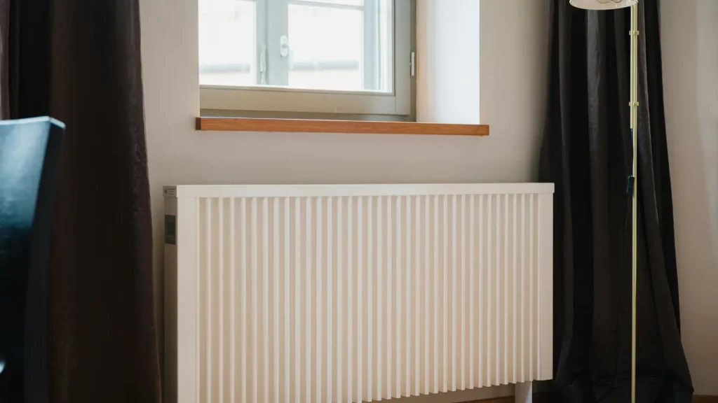 Radiador de aluminio blanco moderno instalado en una pared, dimensionado para trabajar a baja temperatura.