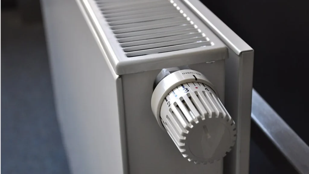Radiador antiguo de agua con válvula termostática en un chalet, compatible con aerotermia de alta temperatura.