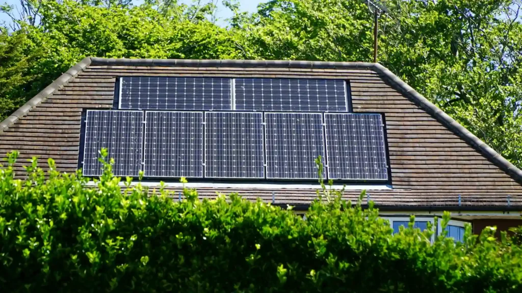 Tejado de vivienda unifamiliar con paneles solares instalados y unidad exterior de aerotermia visible al fondo, combinación de batería térmica solar.