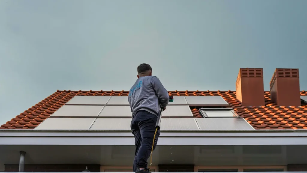 Instalador fotovoltaico en tejado con tableta digital analizando orientación e inclinación de paneles solares, representando el estudio de producción in situ con mediciones reales