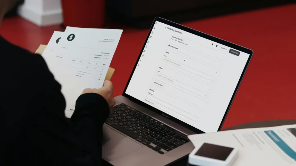 Persona revisando presupuesto técnico en portátil con documentos sobre la mesa, analizando si un pack de aerotermia y placas solares está bien dimensionado