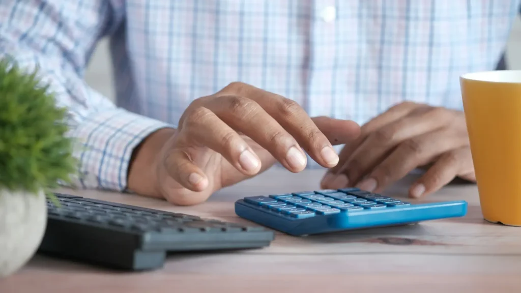 Persona con calculadora y documentos de presupuesto solar sobre escritorio sin datos personales visibles, representando el proceso de análisis comparativo de amortización entre batería física y virtual