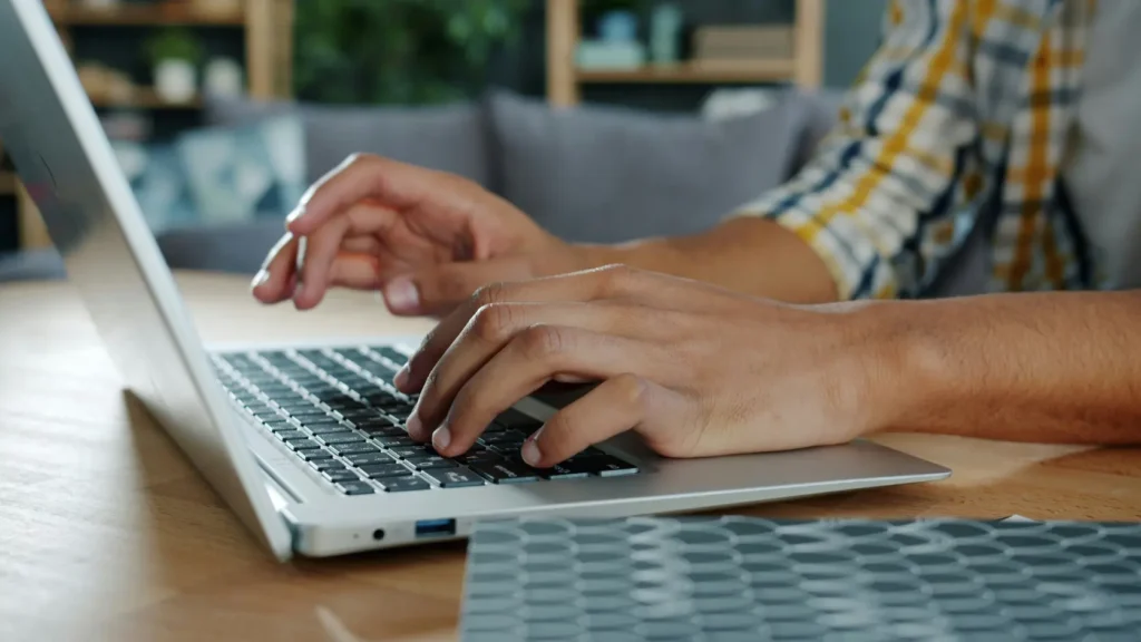 Persona buscando información en portátil con documentos de instalación solar sobre la mesa, representando el proceso de gestionar garantías sin soporte del instalador original