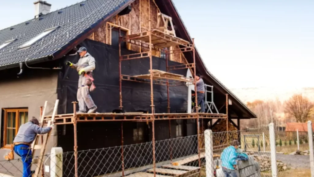 Andamio instalado en fachada de vivienda unifamiliar durante obras de reforma integral, contexto donde la instalación simultánea de aerotermia y solar tiene sentido