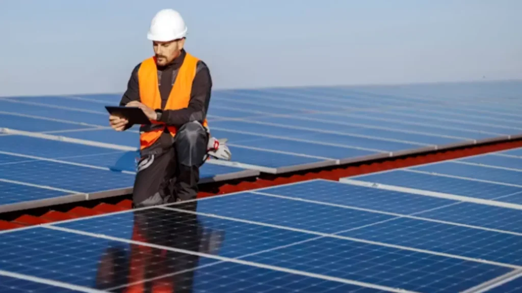 Técnico inspeccionando conexiones eléctricas en parte posterior de paneles solares en tejado, representando las tareas de mantenimiento que no aparecen en los estudios de amortización