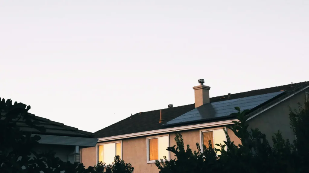 Tejado de vivienda con chimenea proyectando sombra sobre paneles solares desde ángulo lateral, representando la pérdida de producción no modelada en los estudios comerciales
